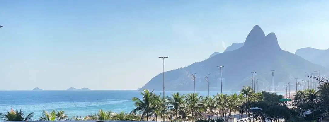 Vista de um rooftop em Ipanema: mar, coqueiros e o Morro Dois Irmãos